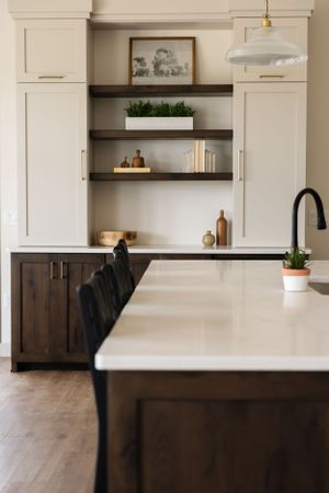 Modern kitchen design with white countertops, dark wood cabinets, floating shelves and pendant lighting.