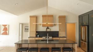 Modern kitchen with wooden cabinets, sleek pendant lights, and a spacious island with bar seating in a contemporary home.