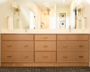 Modern bathroom vanity with light wood cabinets, multiple drawers, and dual mirrors mounted above white sinks.