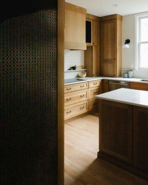 Modern kitchen interior with wooden cabinets, light hardwood floors and white countertops in minimalist design.
