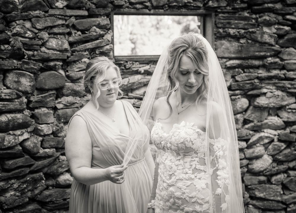 A horizontal collage of wedding moments in black and white shows tender moments between people against a stone wall.