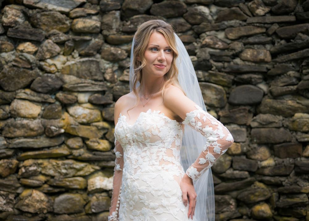 A stone wall creates a rustic backdrop at an outdoor wedding venue.