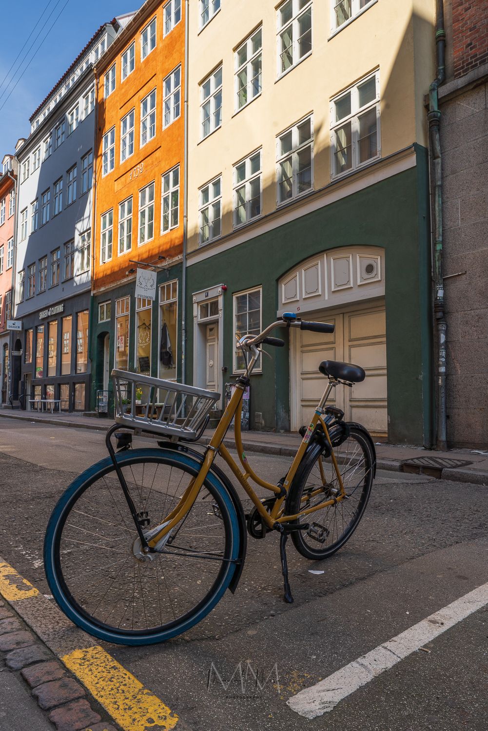 A street photo featuring a yellow bicycle parked on a Copenhagen street.