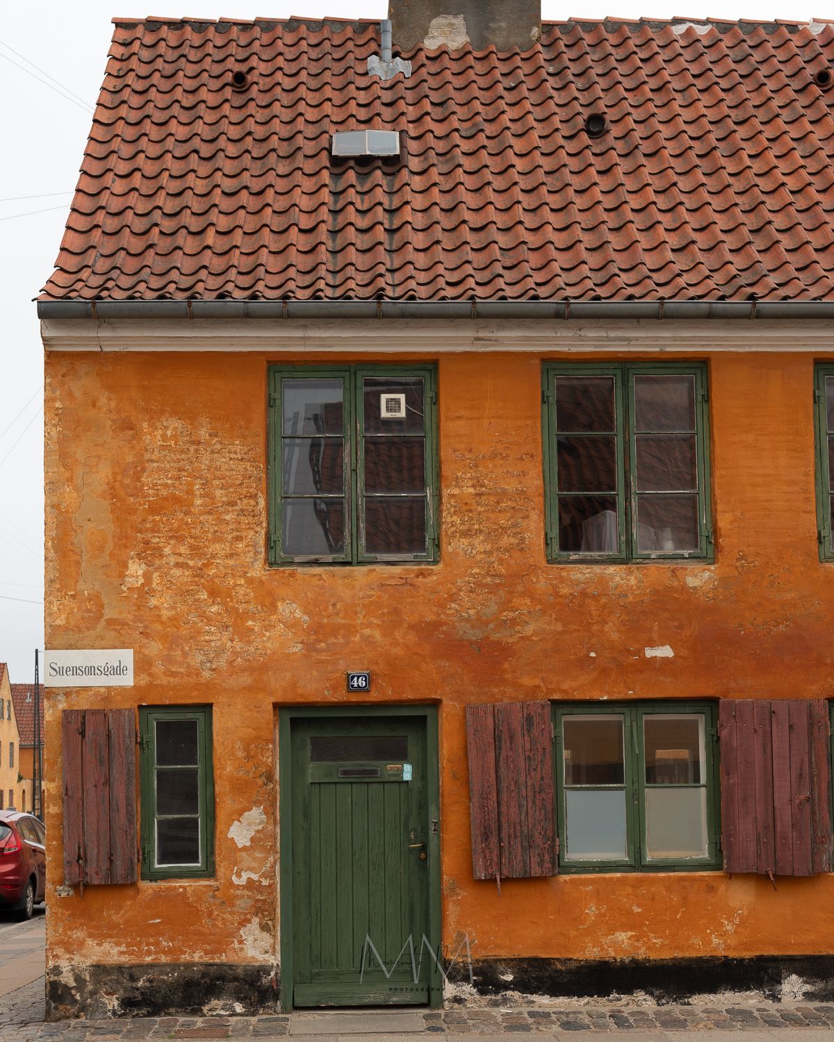 Terracotta roofed, pumpkin-colored building with a dark green door in Copenhagen.