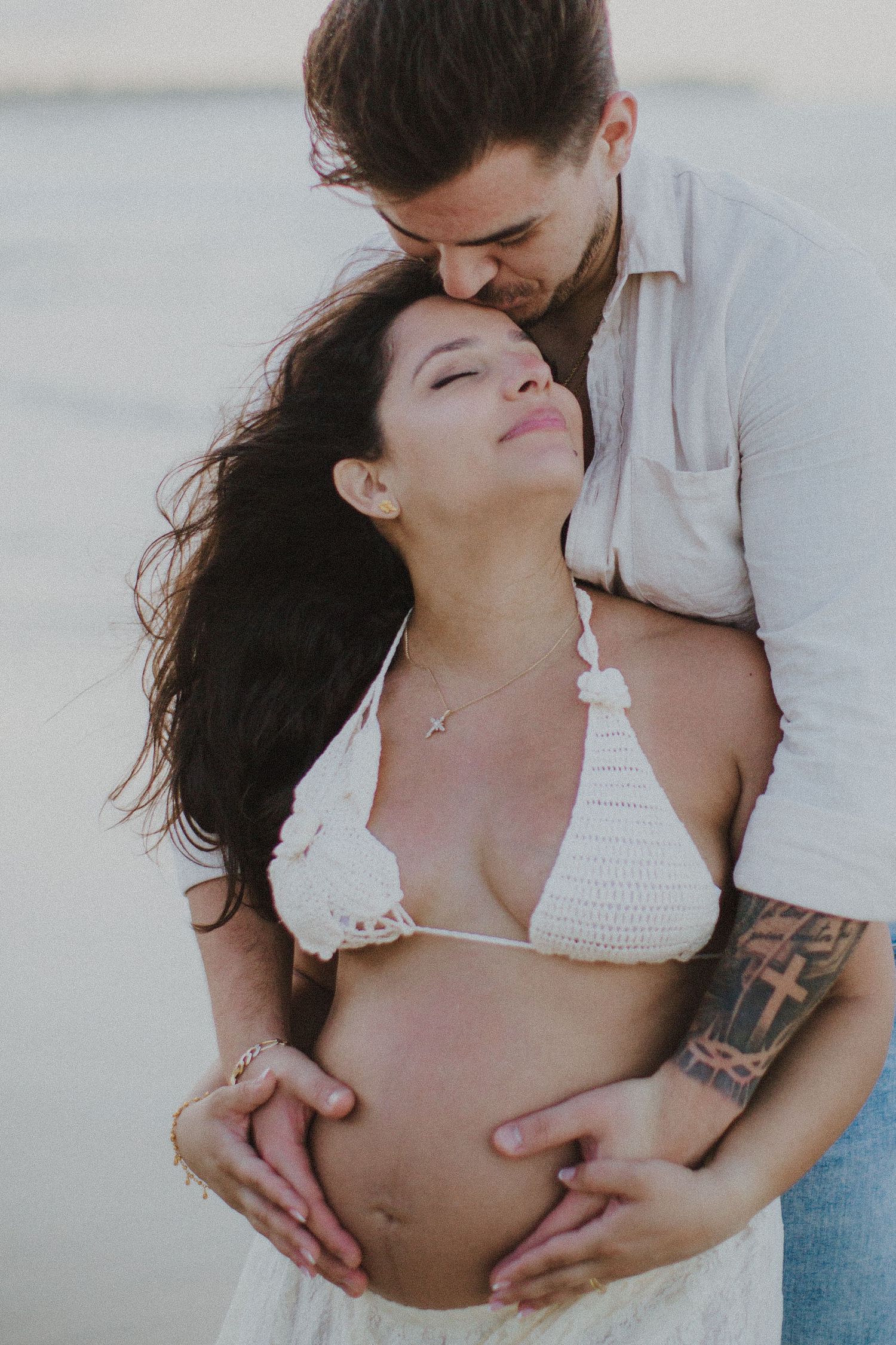 Intimate black and white beach portrait of a couple sharing a tender moment.