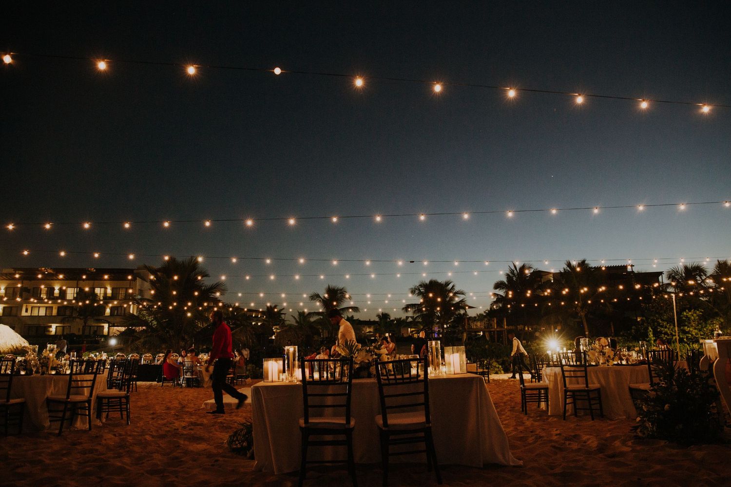 String lights create a romantic ambiance at an outdoor evening wedding reception.