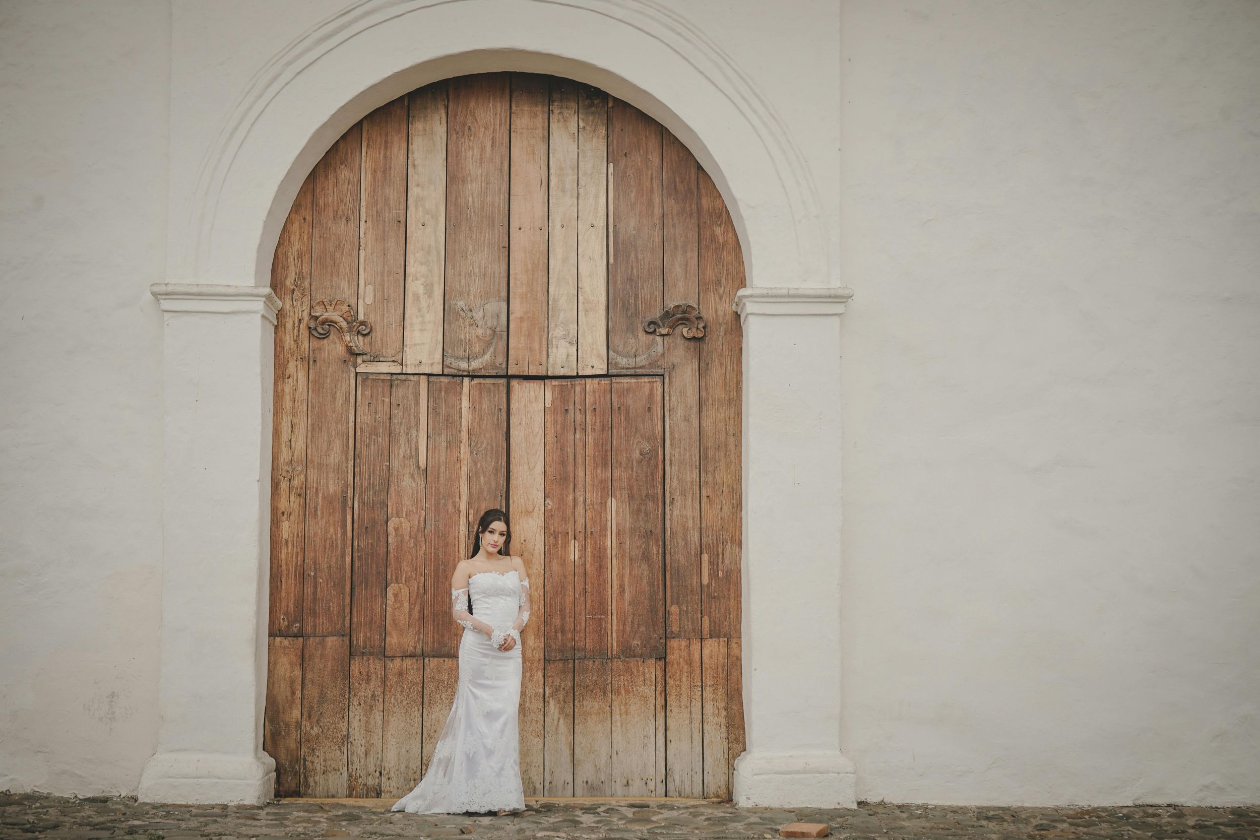 A series of rustic wooden doors against white walls create a vintage backdrop for wedding photography.