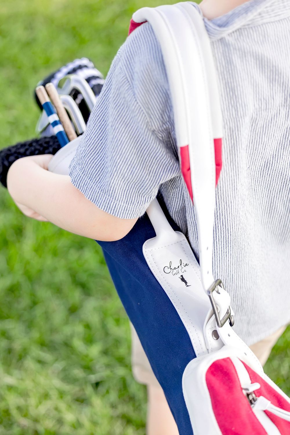Detail of navy and white striped golf apparel with red accents on grass. Charlie Golf Co. Branding Photographer Clear Lake Iowa, Brand Photo
