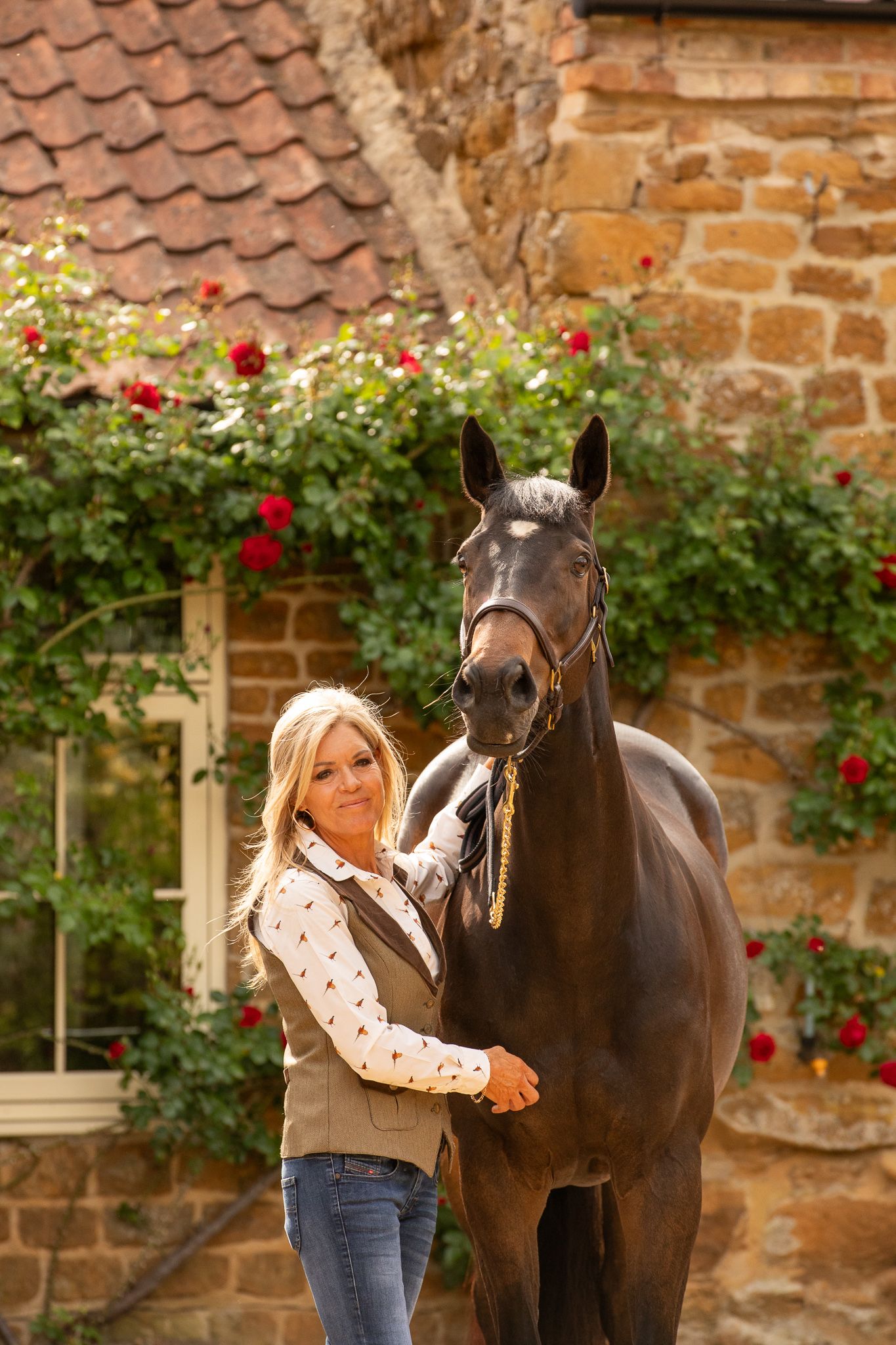 A gentle moment between a rider and dark horse with white blaze in a rustic stable setting, captured in black and white.