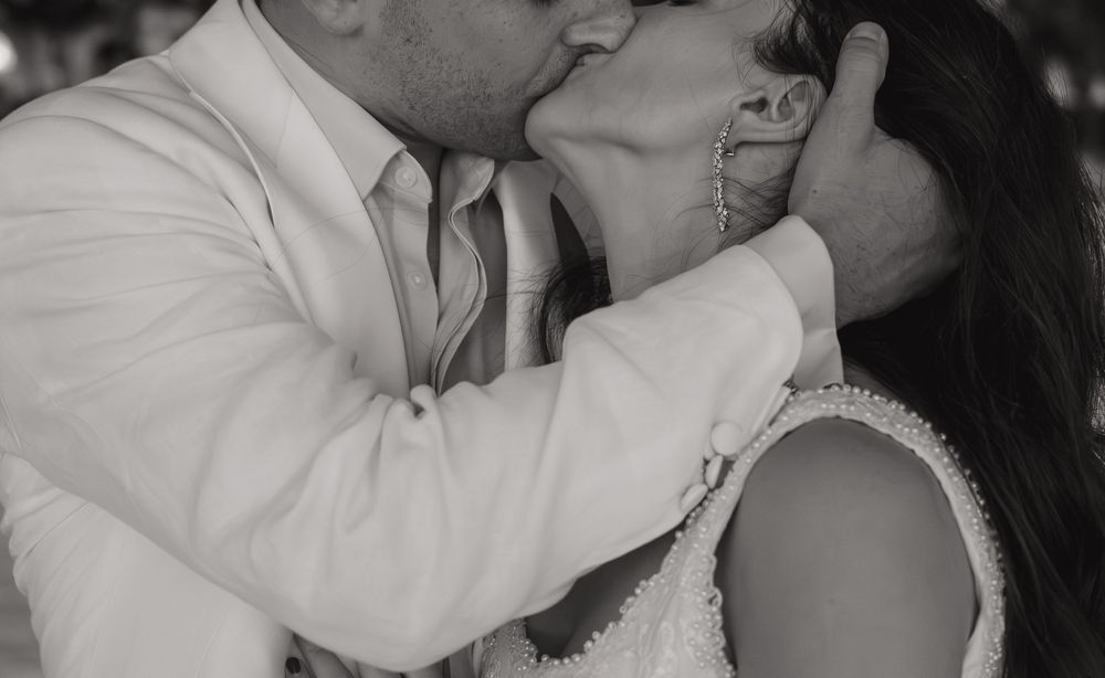 Black and white close-up shot of a romantic kiss between a couple in formal wedding attire.