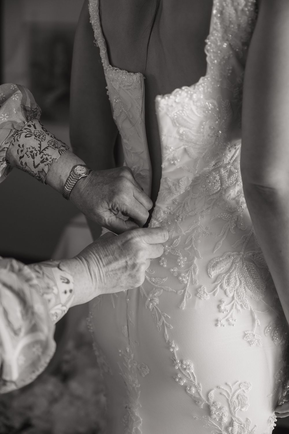 Close-up of delicate lace wedding dress being fastened.