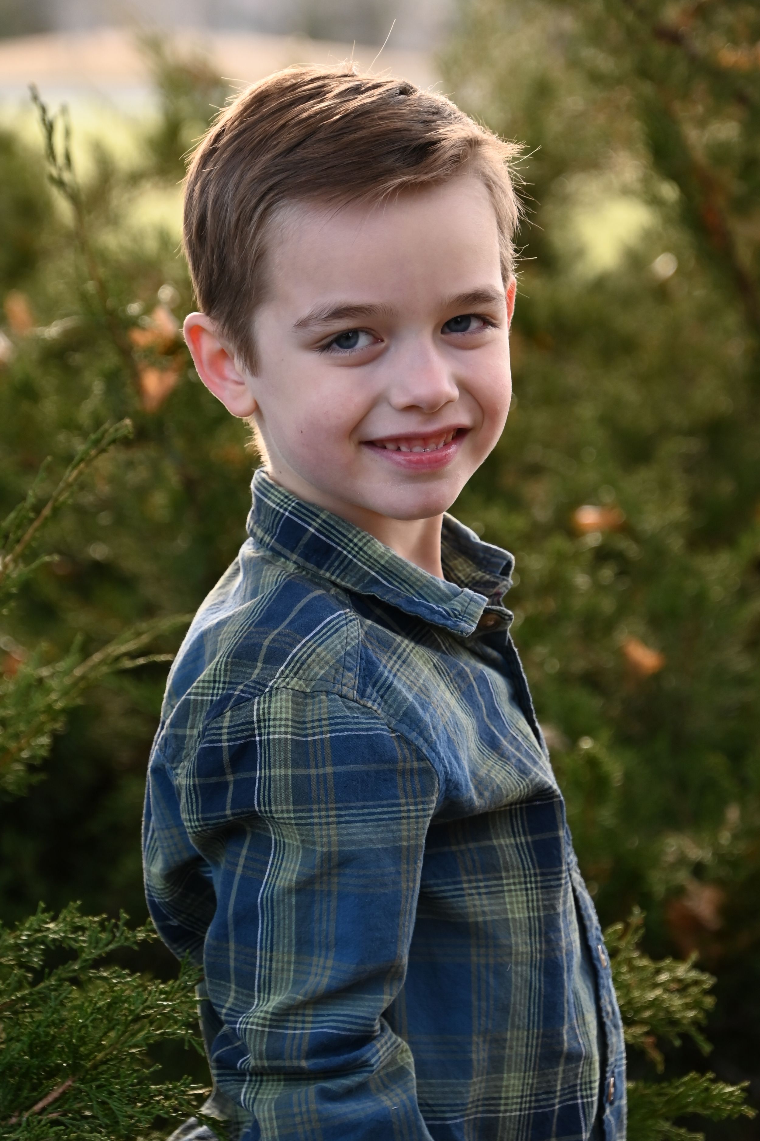 A series of four outdoor portrait photos showing someone wearing a blue plaid shirt against a natural green background.
