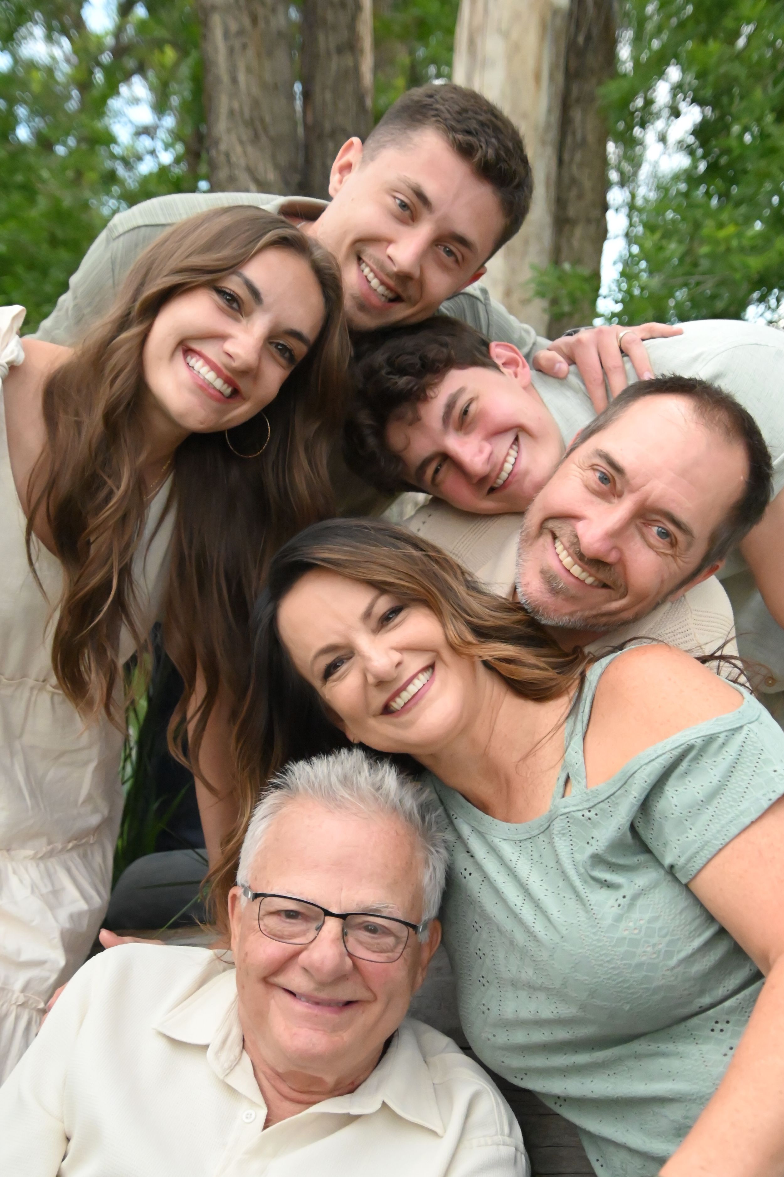 Cheerful group poses for a collage of selfie photos while leaning in together outdoors on a sunny day.