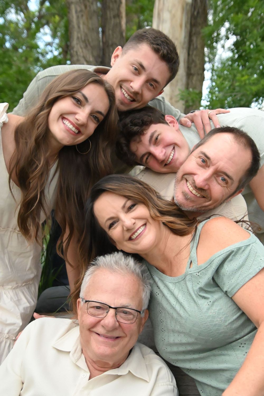 Cheerful group poses for a collage of selfie photos while leaning in together outdoors on a sunny day.