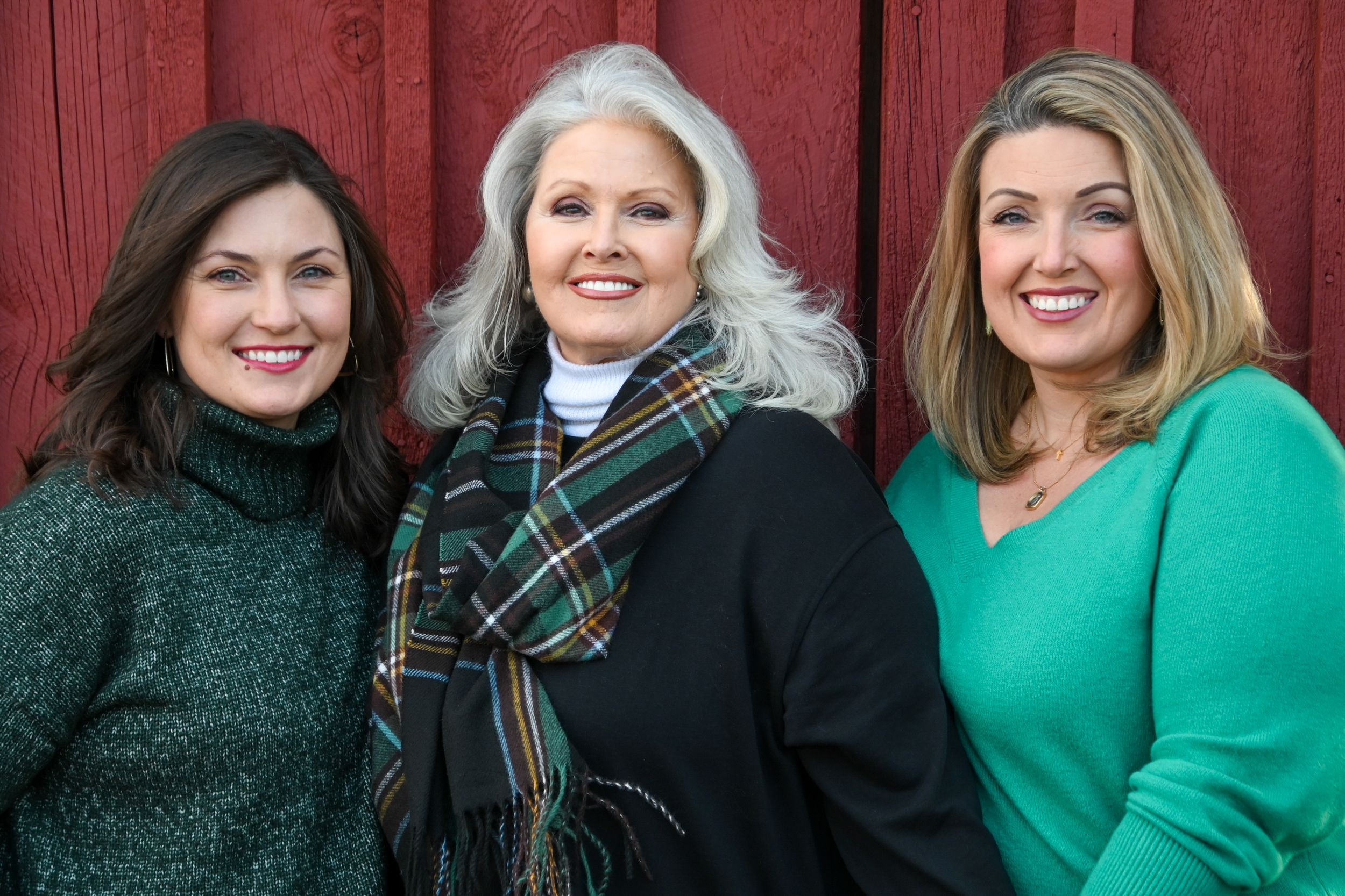 A group of women wearing green and black outfits pose together for a festive holiday photo.