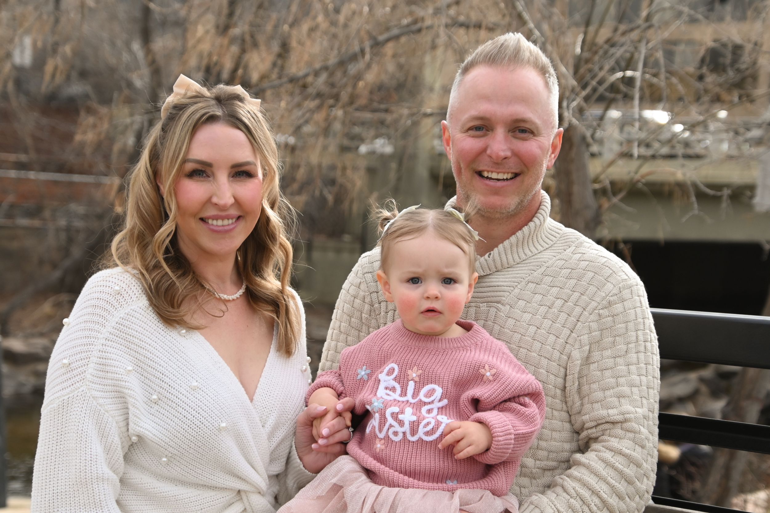 A family wearing coordinated cream and pink outfits poses together for outdoor portrait photos in multiple poses.
