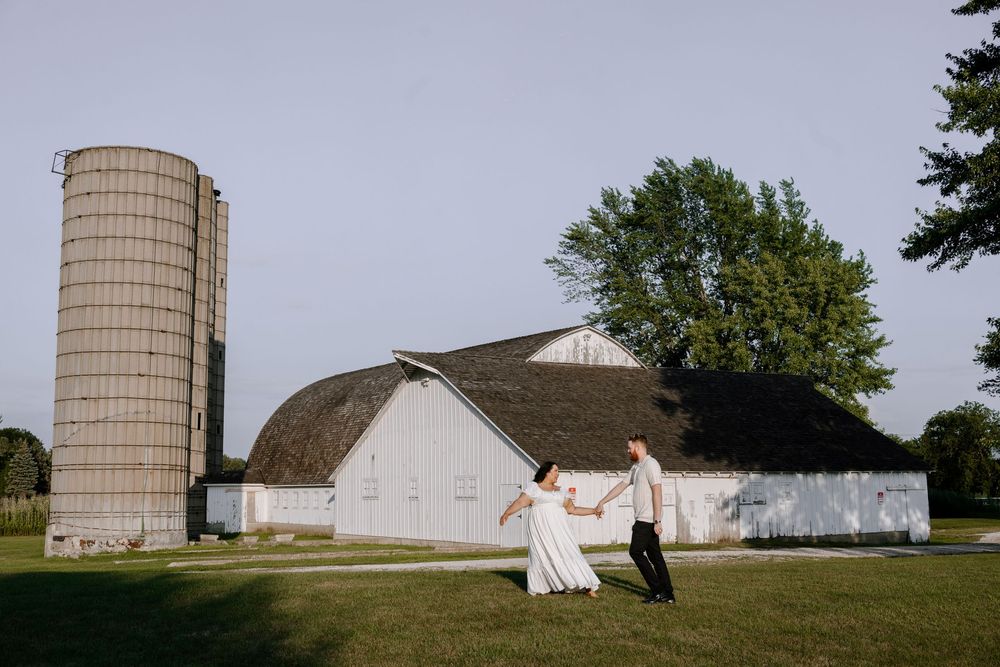 A romantic dance pose in front of a white barn and silo on a rural farm.