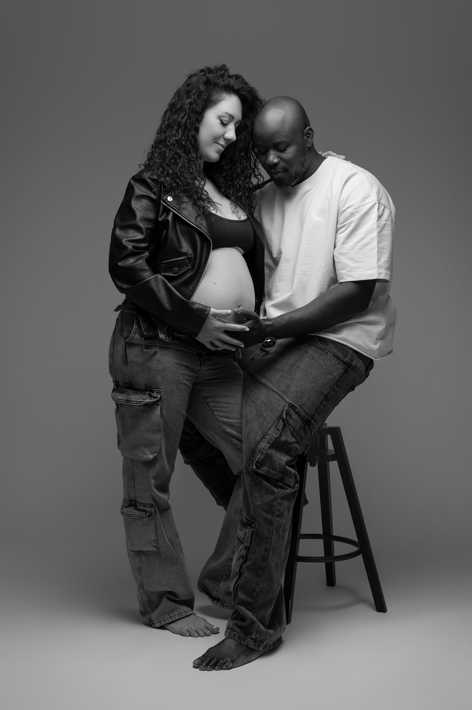 Black and white artistic portrait series showing intimate moments between two people sitting on a stool.