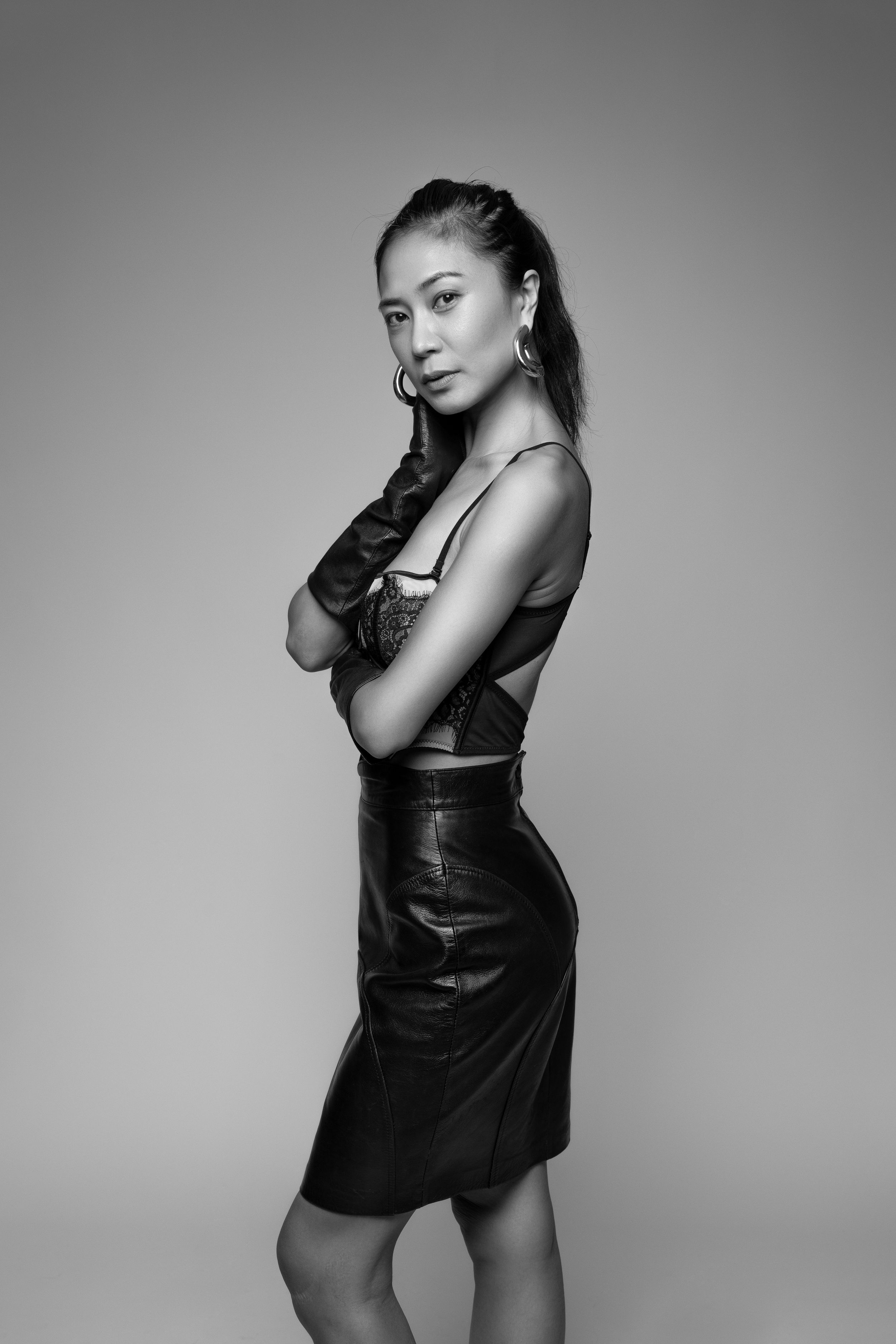 Professional black and white fashion photoshoot sequence showing model in leather dress posing against studio backdrop.
