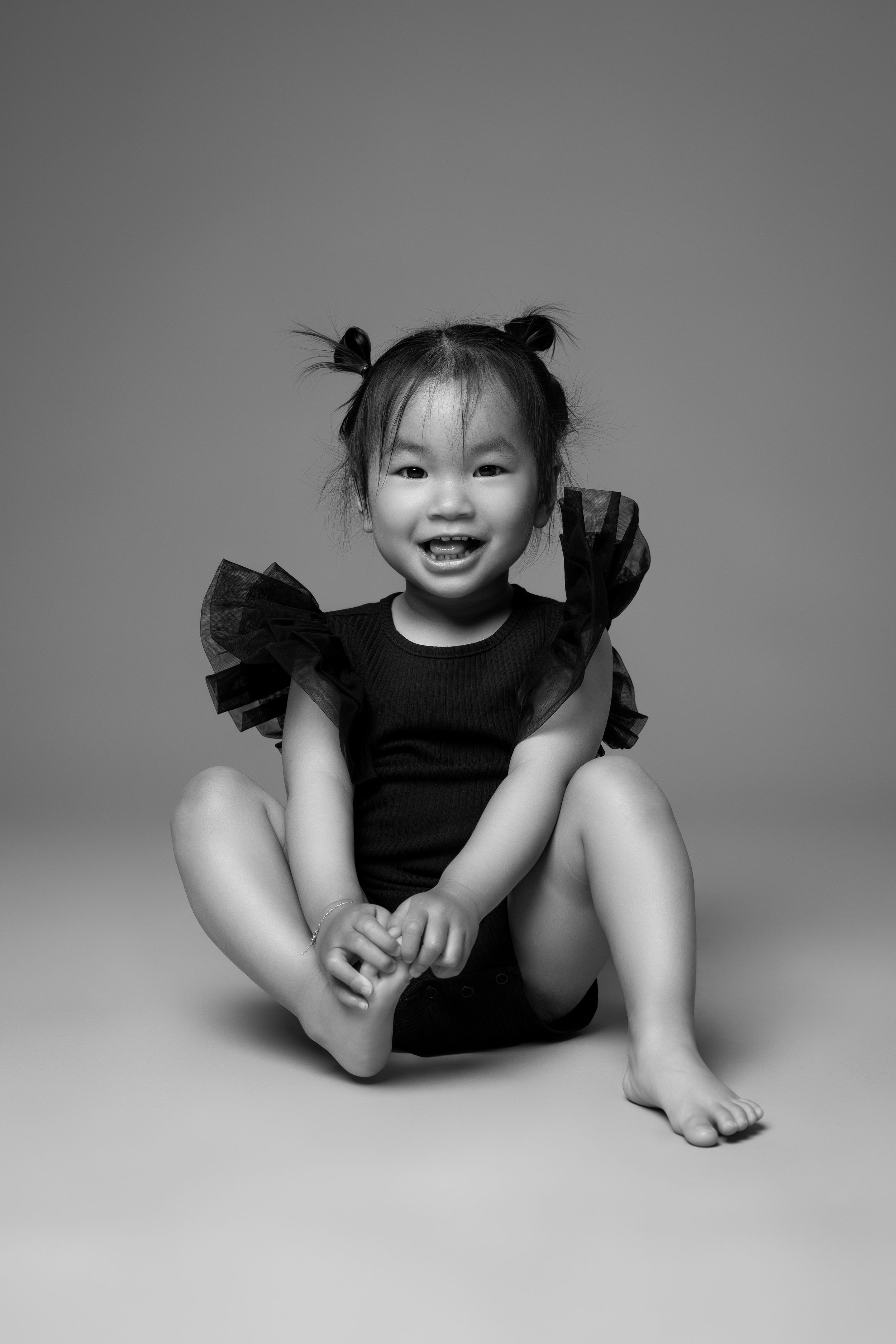 Black and white artistic photo strip sequence showing joyful expressions and playful poses on a light background.