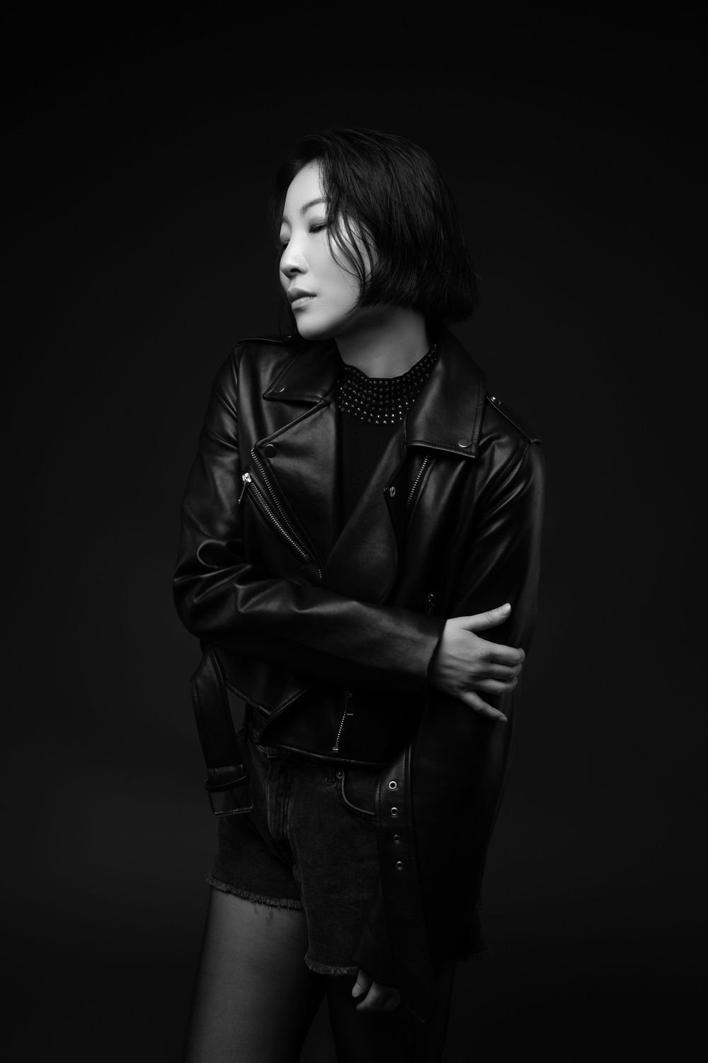 Atmospheric black and white portrait of a figure wearing a leather jacket against a dark background.