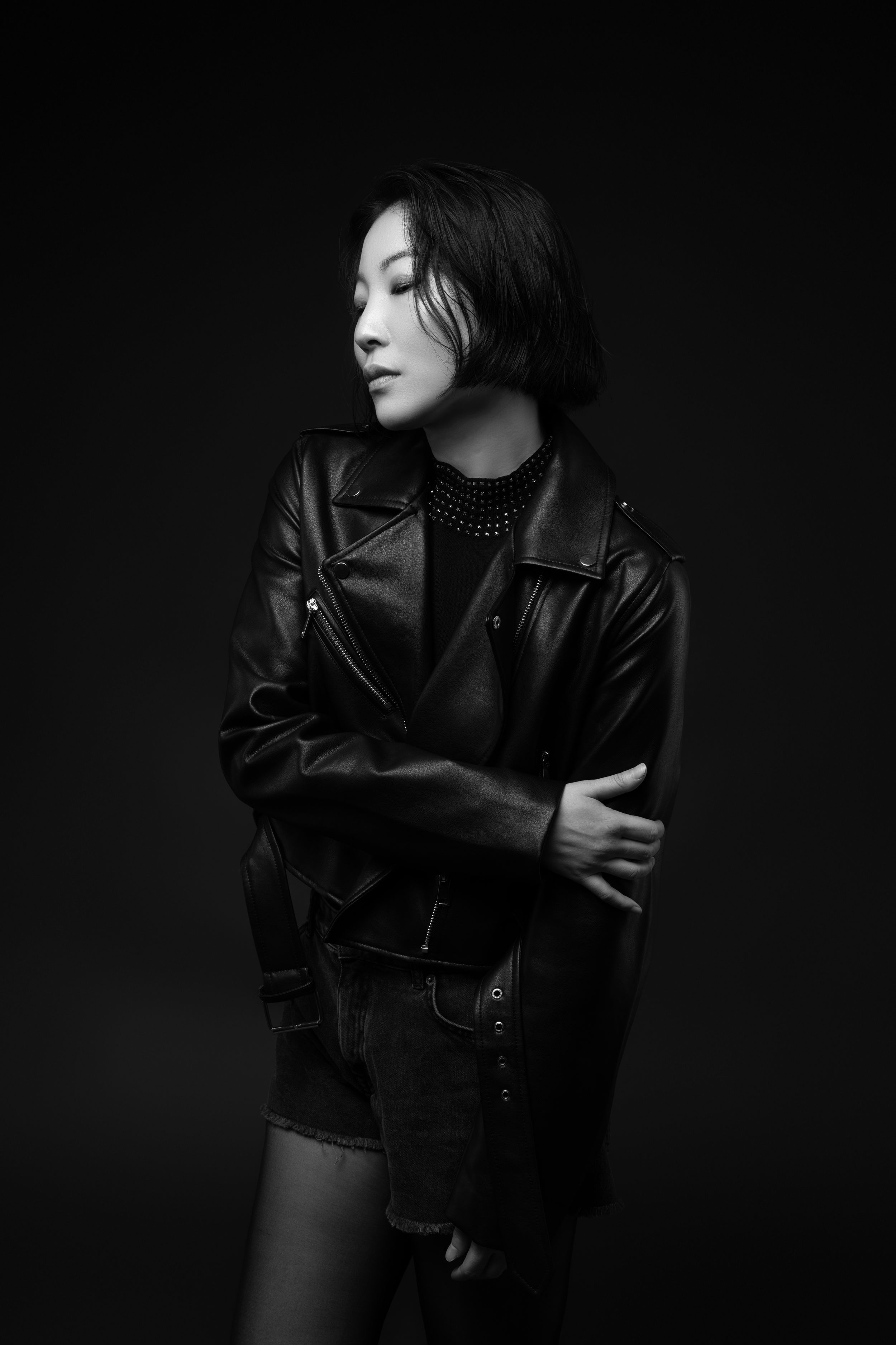 Atmospheric black and white portrait of a figure wearing a leather jacket against a dark background.