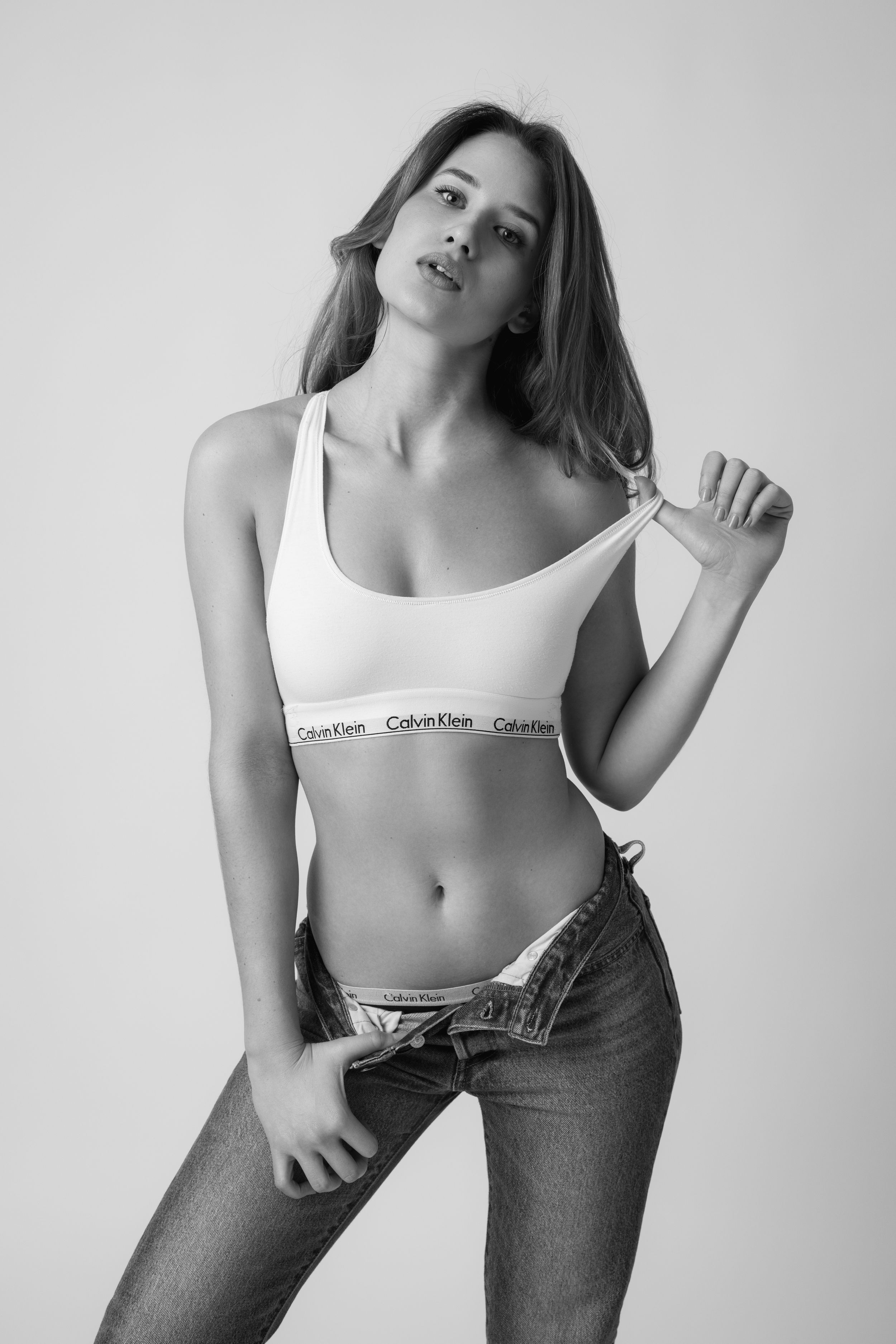 Fashion model in casual white top and denim creates dynamic poses in studio setting.