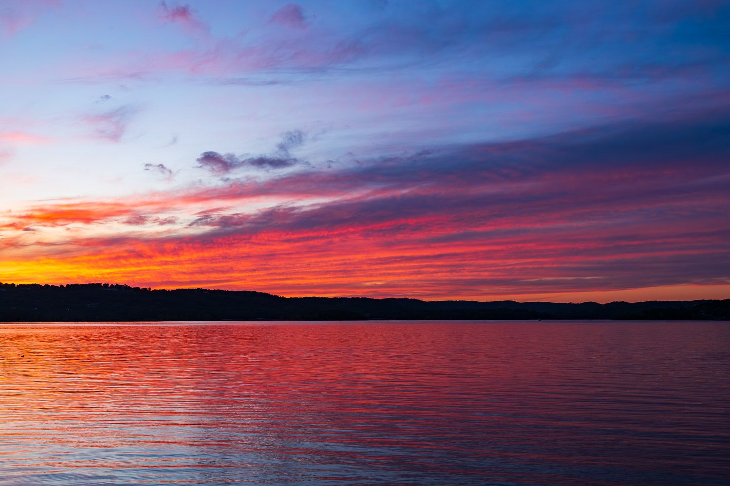 Stunning vivid pink and purple sunset reflecting over calm lake waters. Table Rock Lake Indian Point Missouri