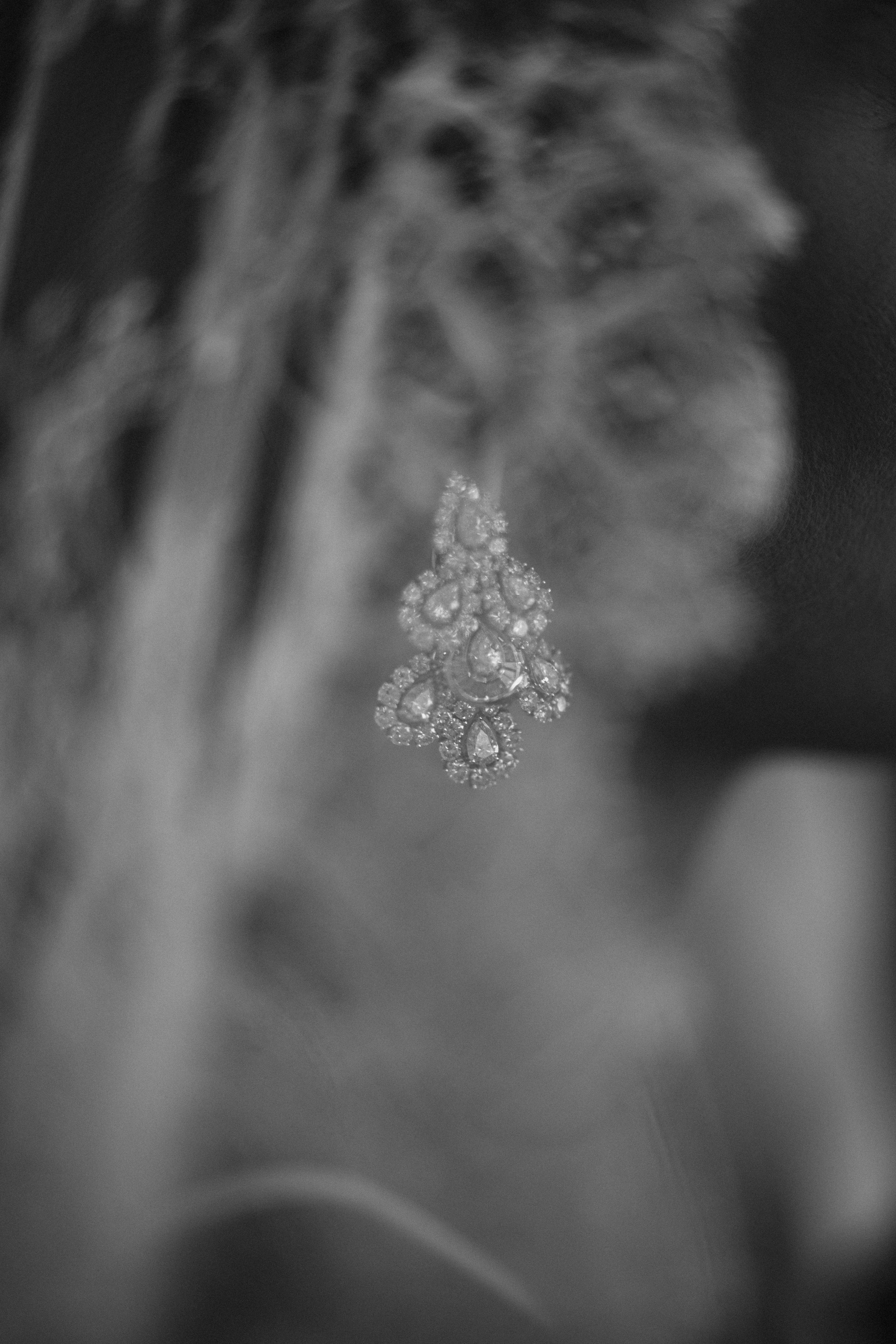 Delicate floral diamond earring sparkles in black and white photography.