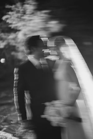 Artistic black and white wedding photo showing silhouettes in soft focus with dreamy motion blur effects.