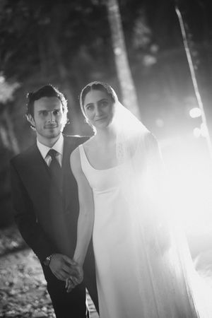 Black and white wedding photo of a couple posing outdoors with ethereal lighting and a dreamy atmosphere.