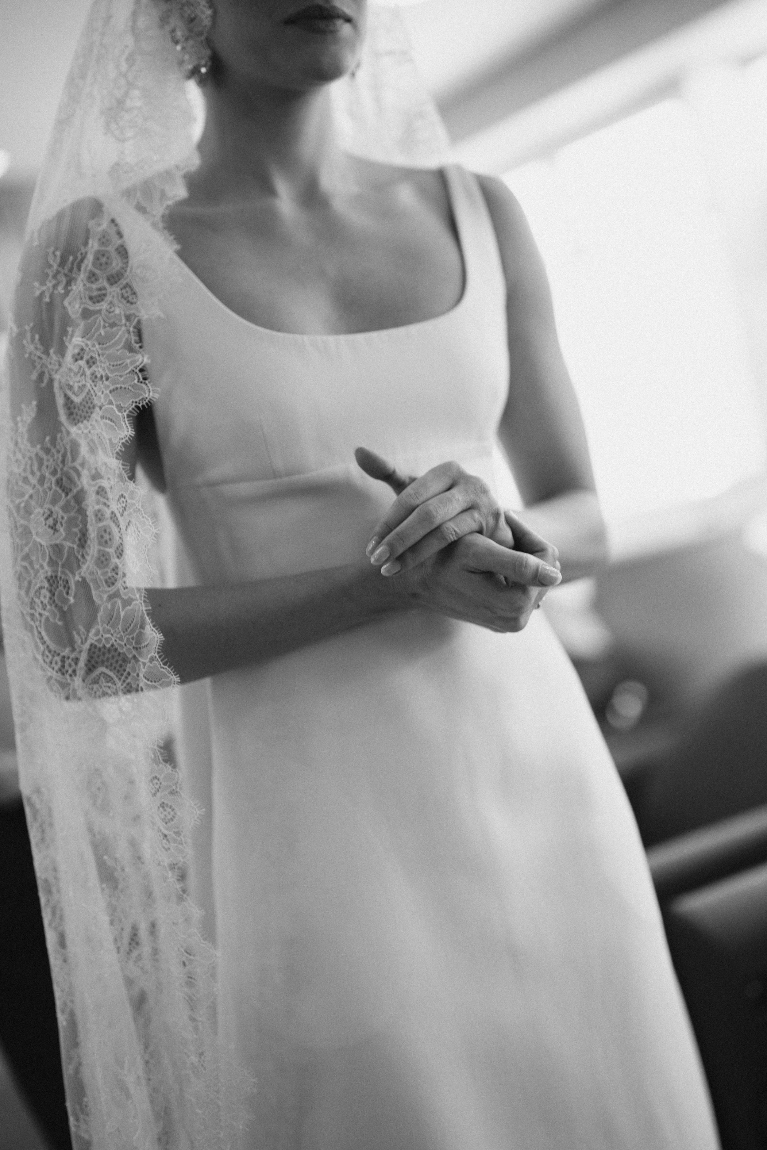 Close-up details of a delicate white lace wedding dress in black and white photography.