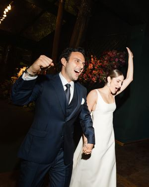Wedding couple joyfully dancing and celebrating at their nighttime garden reception.