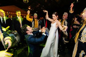 Wedding celebration with people dancing and celebrating on a dance floor under yellow lighting at night.