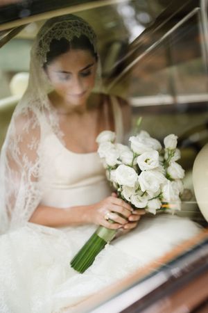 Elegant bridal bouquet of white roses and flowers held in a white lace gown.