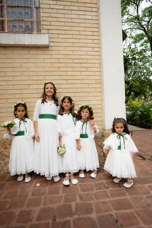 A sequence of five photos showing children in white dresses posing on brick steps against a tan wall.