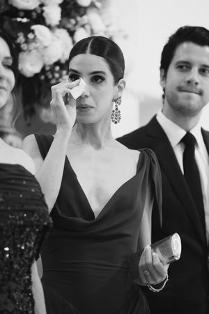 A group in formal black and white attire pose at an elegant event with white floral decorations in the background.