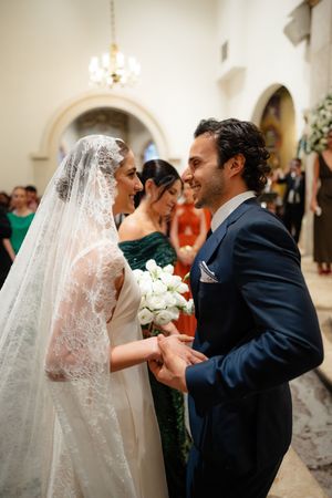 A tender wedding moment shows a couple sharing a romantic kiss while holding a white floral bouquet.