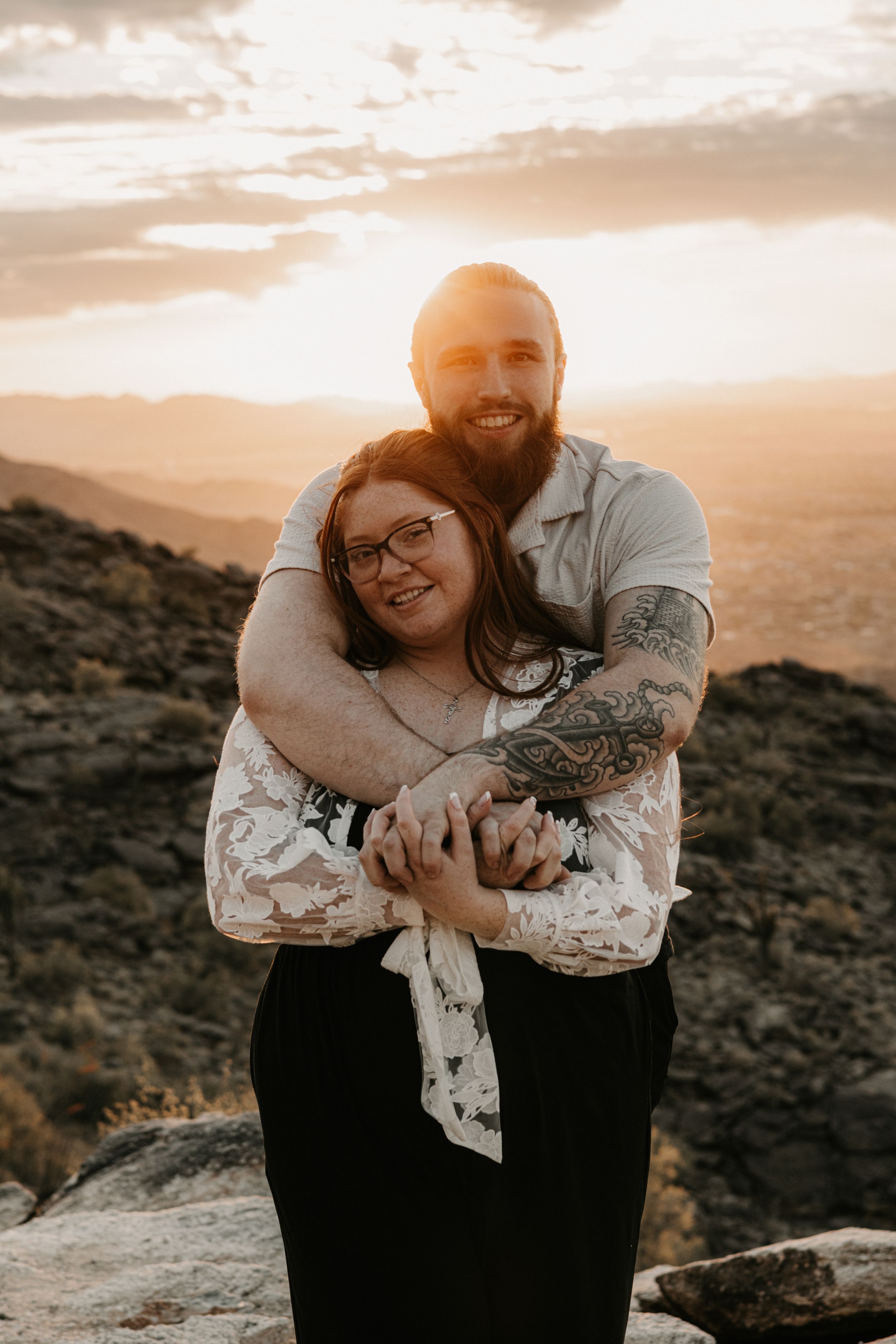 Couple holding each other during sunset engagement photos in Arizona.