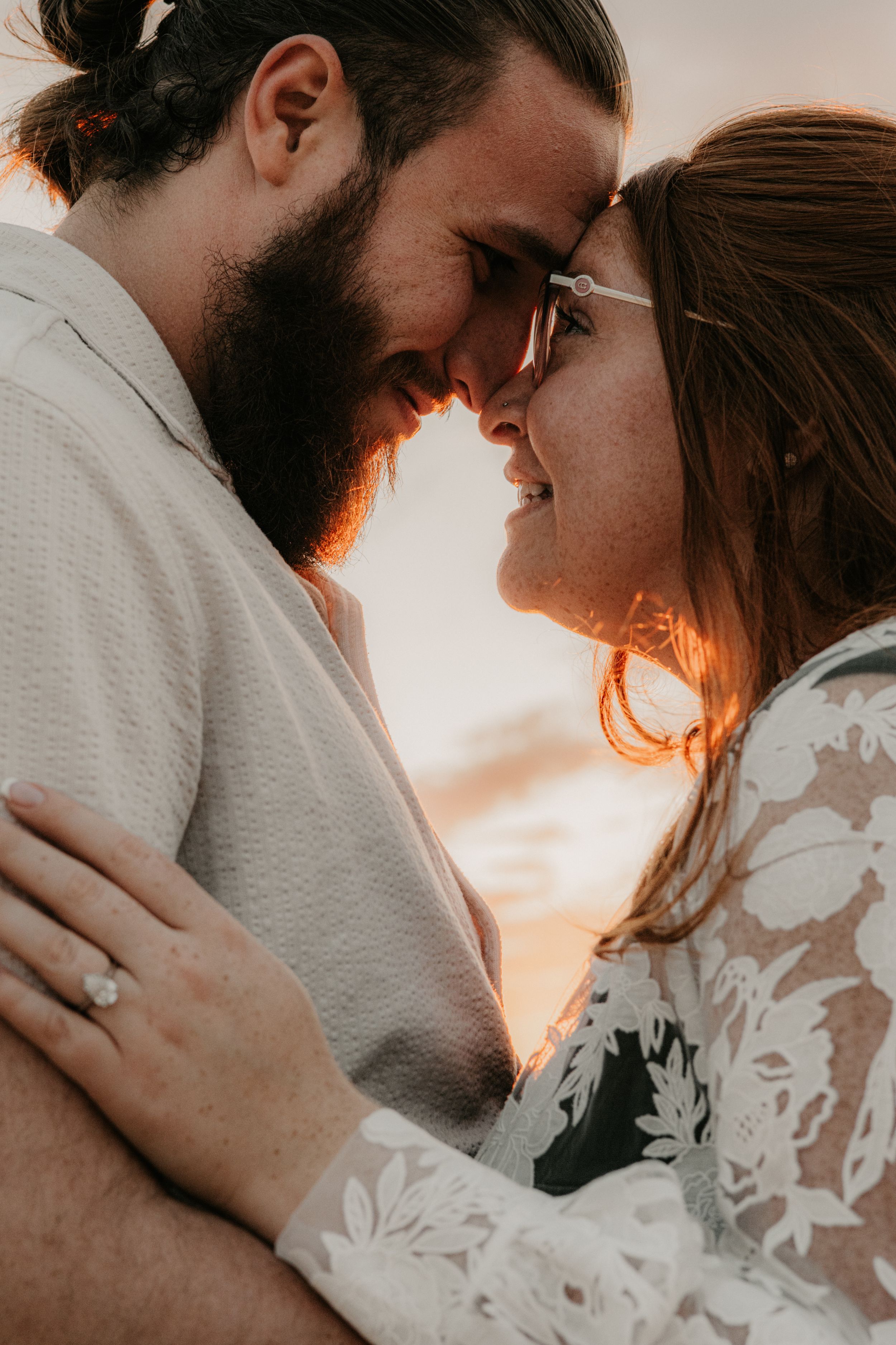 Couple laughing together during a warm and moody engagement session in Arizona.