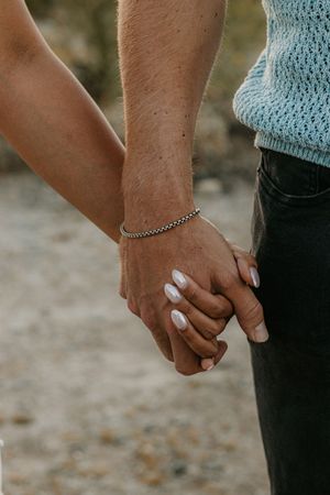 Couple holding hands together beneath desert mountains in Sedona Arizona.