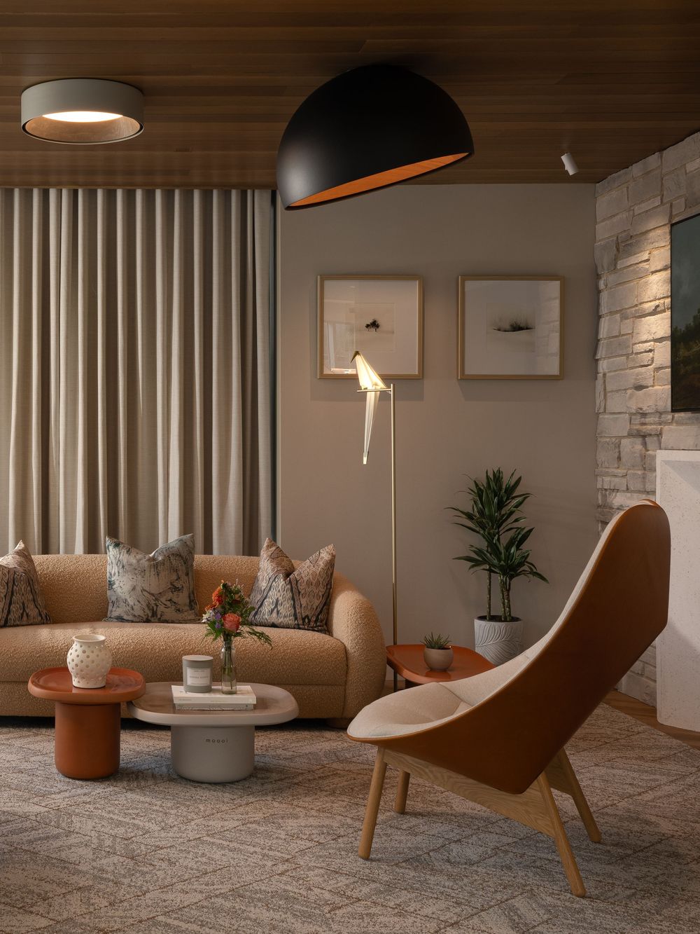 Modern minimalist living room interior with stone wall, curved lounge chair, and contemporary lighting design.