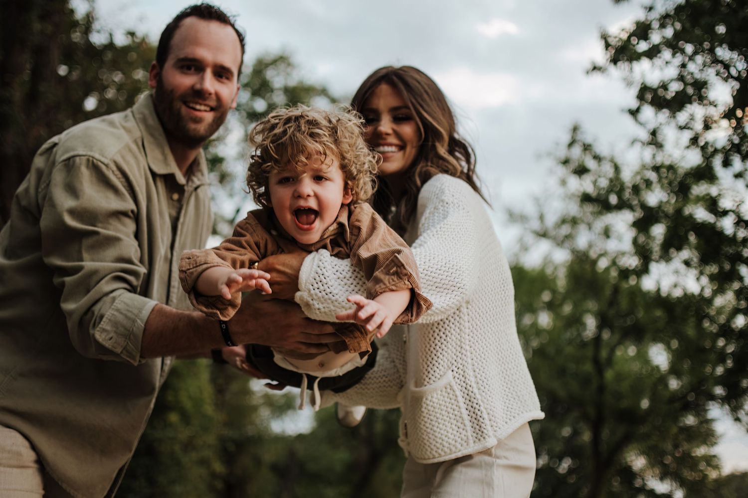 Intimate couple in light-colored clothing sharing joyful moments together outdoors during a photo session.