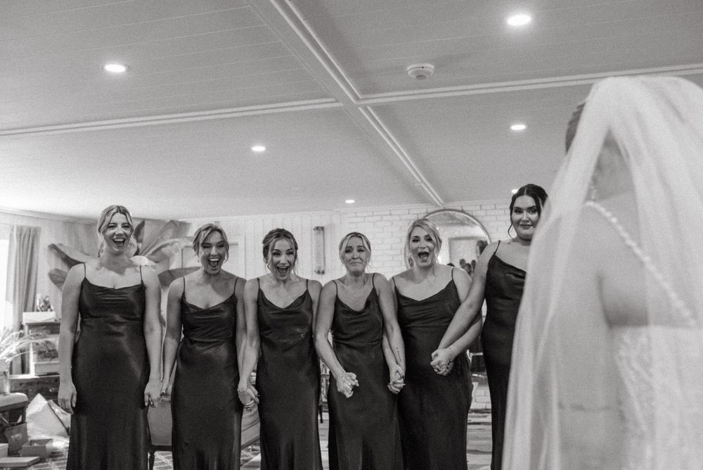 Black and white photo strip sequence showing joyful wedding preparation moments with bridesmaids in matching dark dresses.