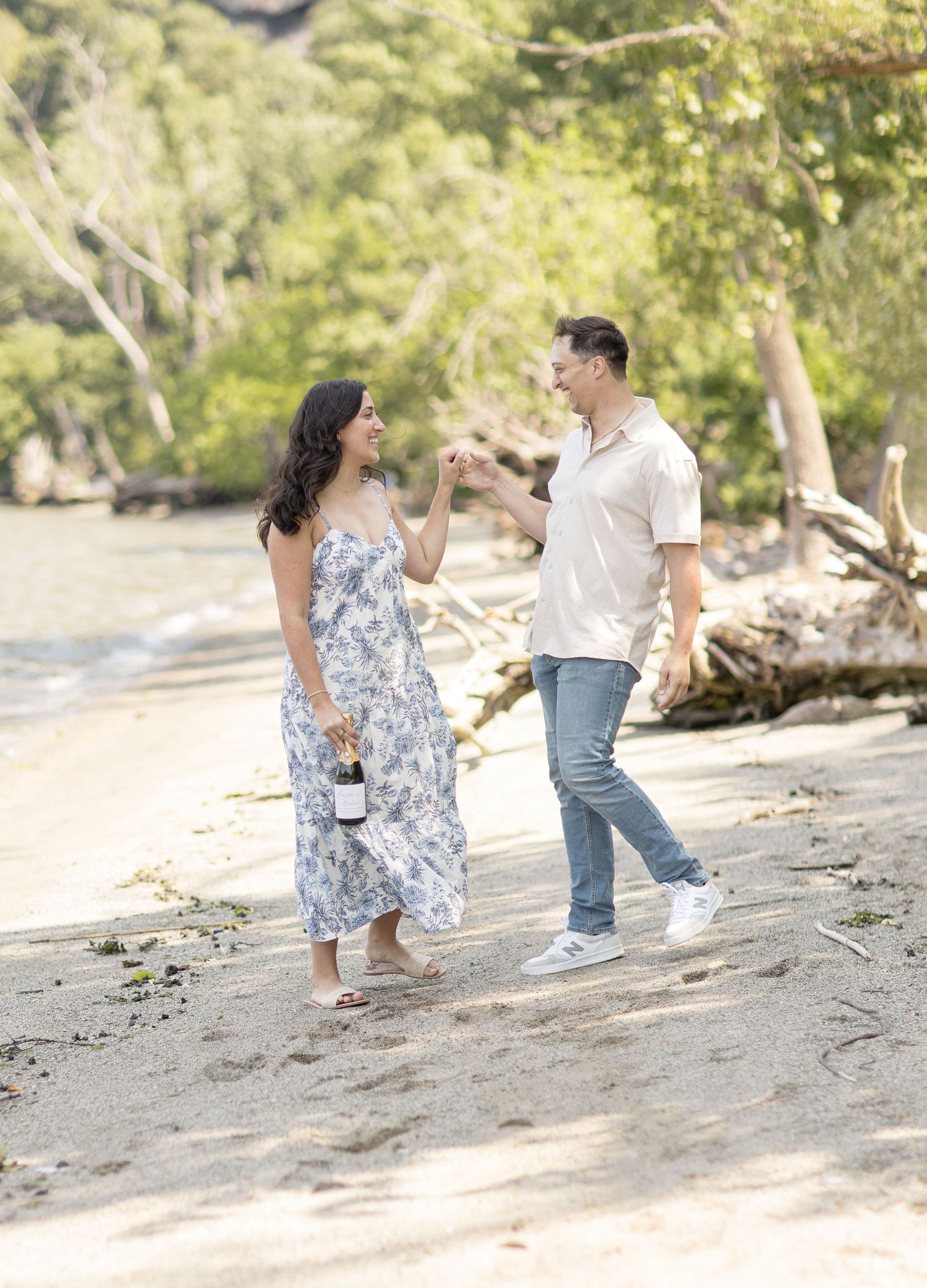 A couple walking together on a beach path in casual attire with trees and natural scenery in the background.