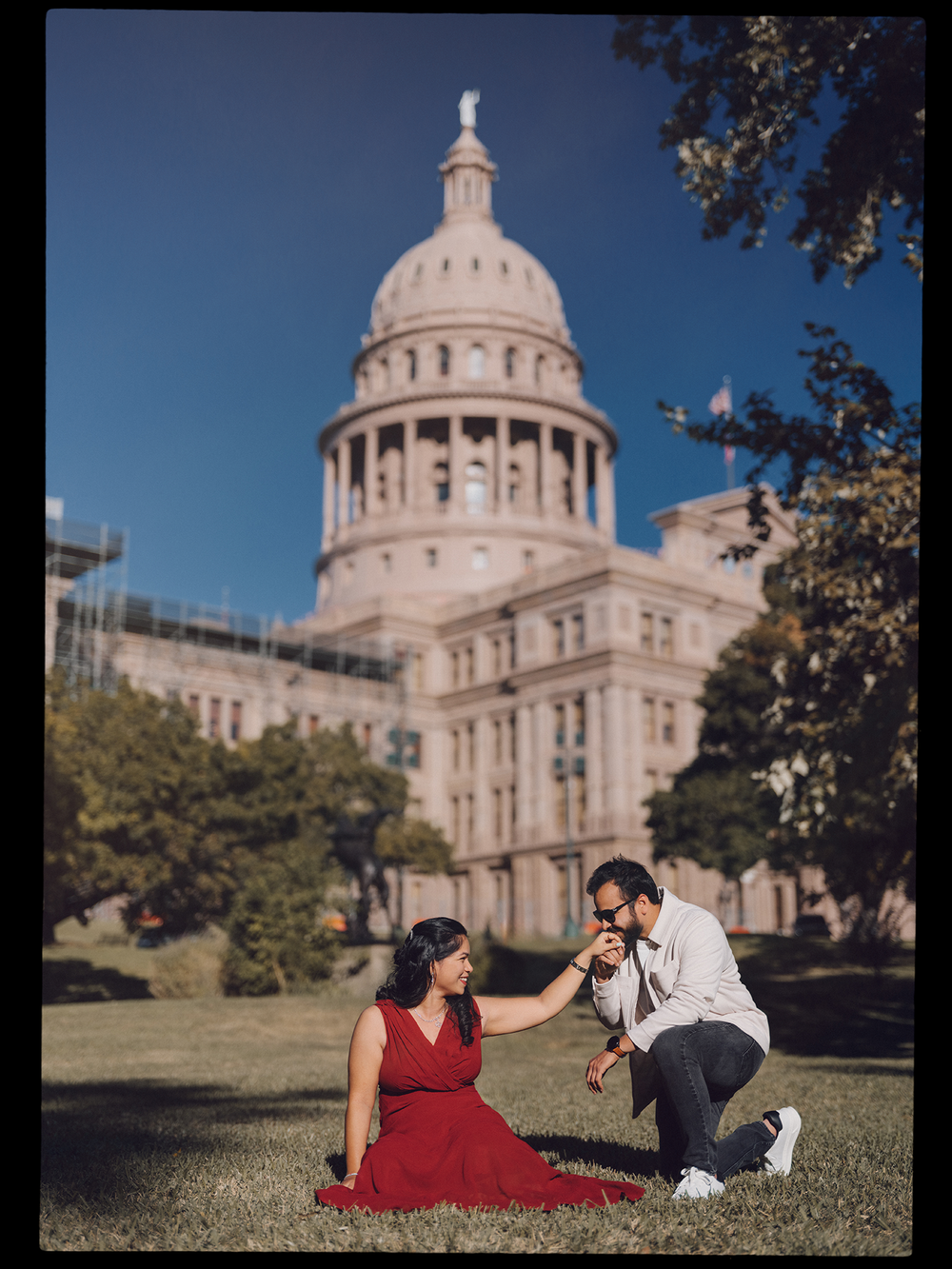 A couple enjoys a romantic moment on the lawn in front of the Texas State Capitol building in Austin.