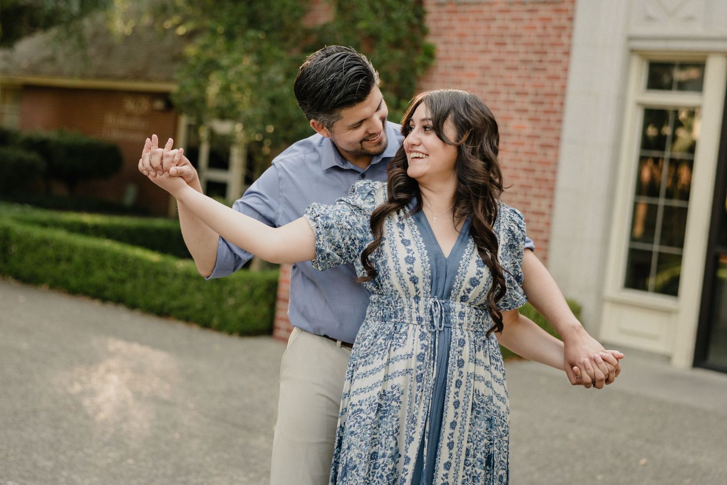 Beautiful couple walking between stone columns and brick buildings at a university campus.