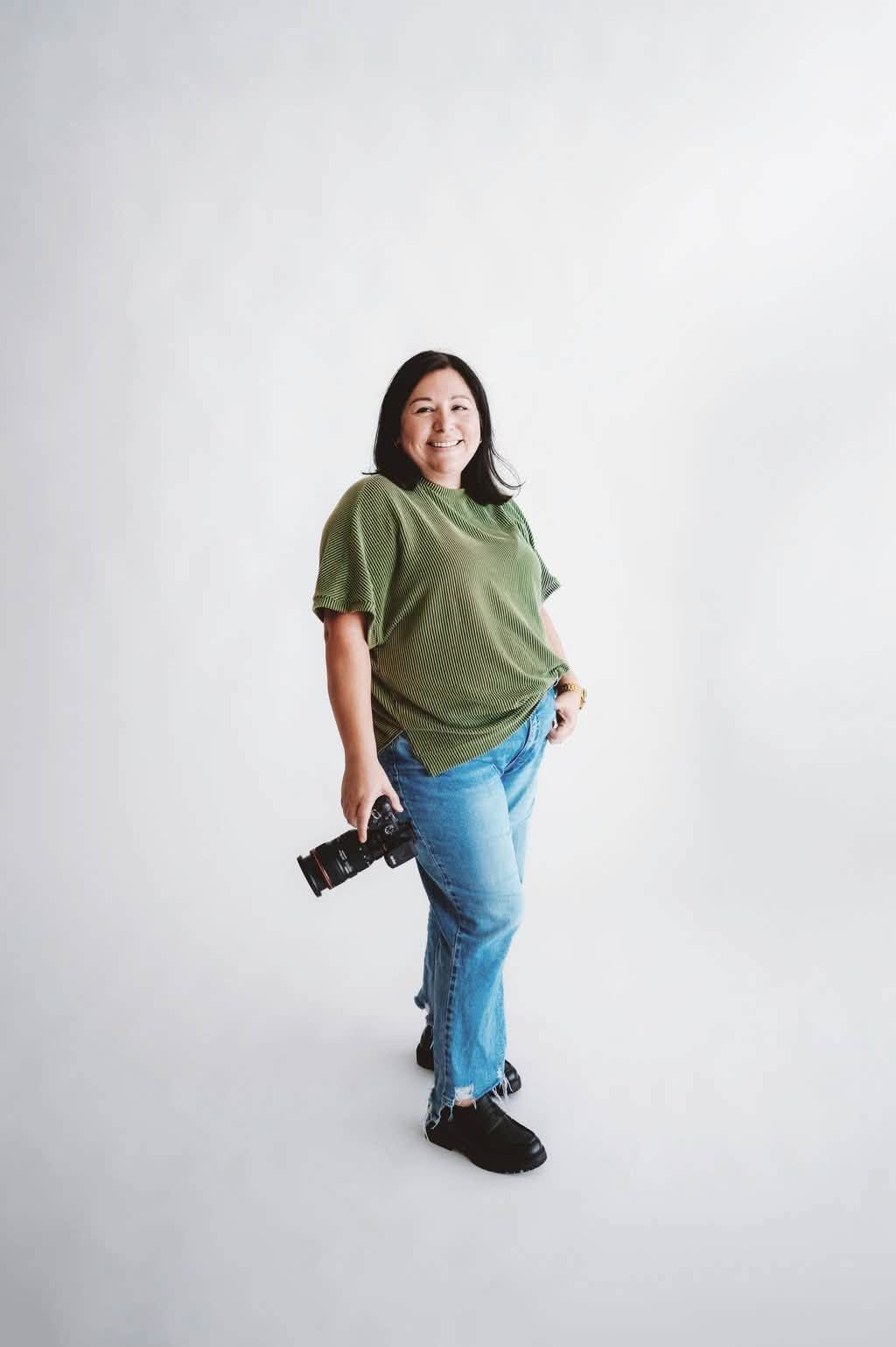 Person in orange jacket and jeans poses playfully against green background.