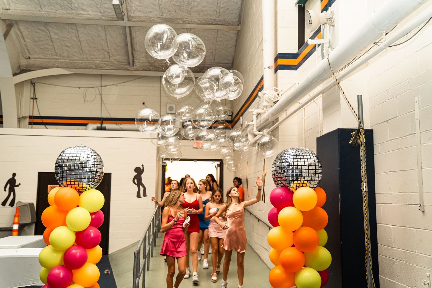 Party decorations with balloons and disco balls in white indoor space.
