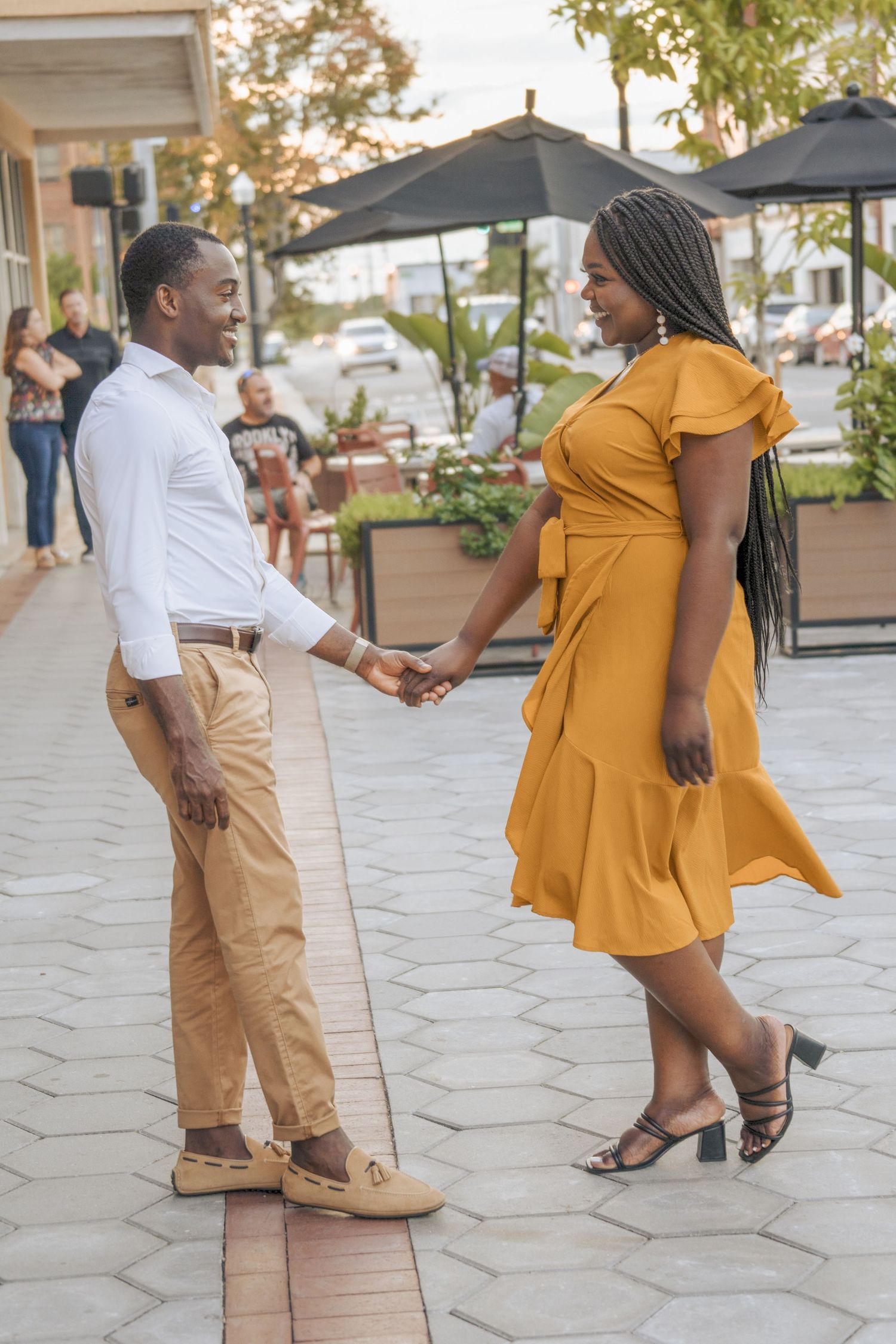 A couple holds hands while enjoying a romantic moment on a paved walkway.